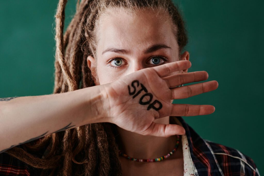 pexels-photo-8689920-8689920 Close-up of a woman holding her hand marked with 'stop' in front of her face, symbolizing protest and strength.